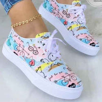 White women's sneakers with colorful graffiti design details and chunky soles on a plain background.