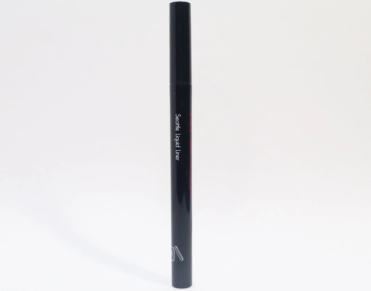 Queen Anne Liquid Liner pen closed, resting on a wooden surface with a blurred background.