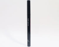 Queen Anne Liquid Liner pen closed, resting on a wooden surface with a blurred background.