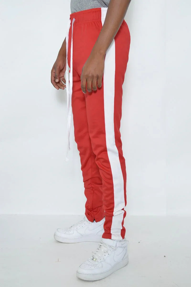 Model wearing red slim fit track pants standing, showing side and front details.