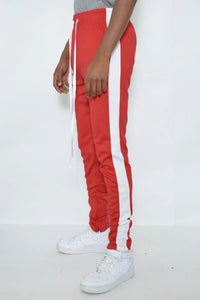 Model wearing red slim fit track pants standing, showing side and front details.