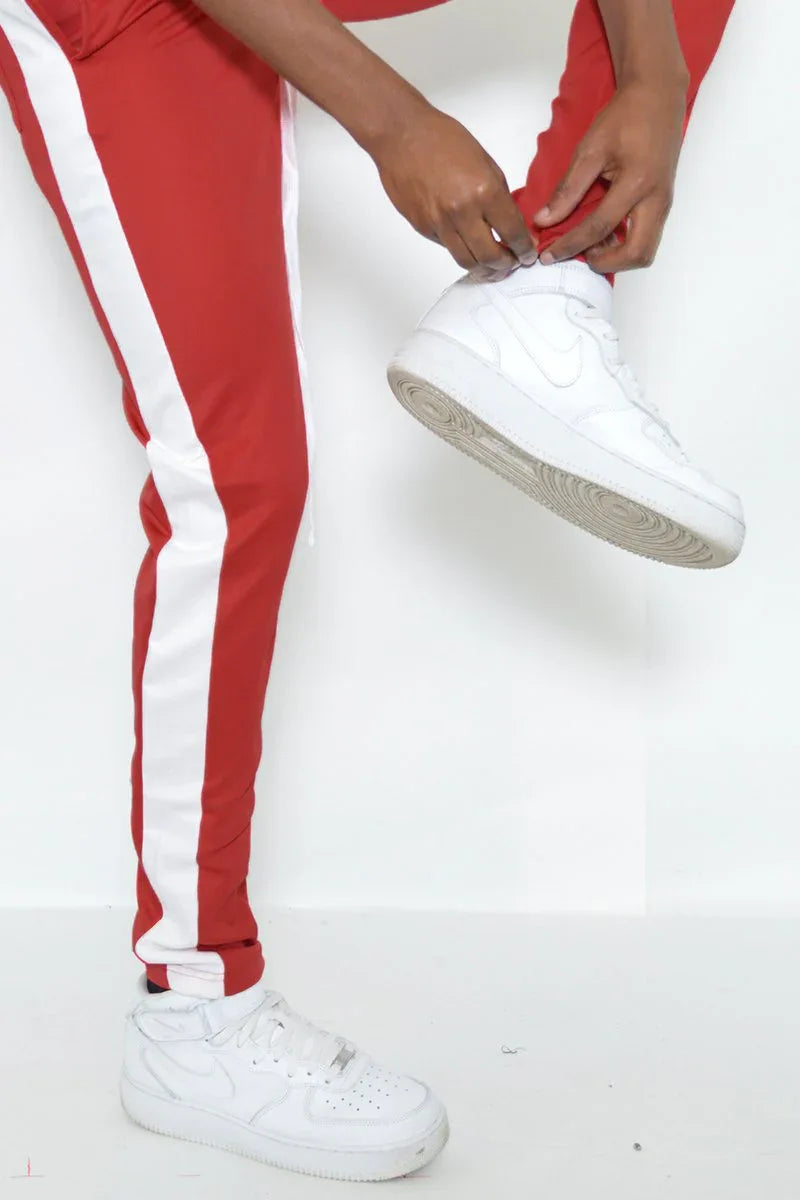 Rear view of red slim fit track pants highlighting zipper and stripe details.