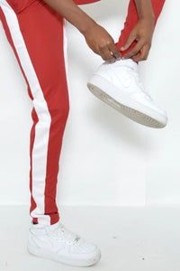 Rear view of red slim fit track pants highlighting zipper and stripe details.