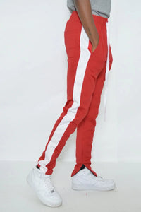 Red slim fit men's track pants with single white stripe detail, angled front view.
