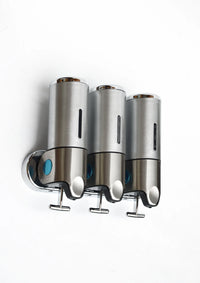 Stainless steel wall-mounted shower dispenser with three clear liquid containers and pump nozzles.