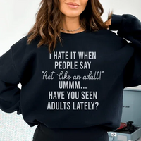 Black sweatshirt featuring 'Act Like An Adult' in peach text, highlighting cozy fleece fabric and fitted design.