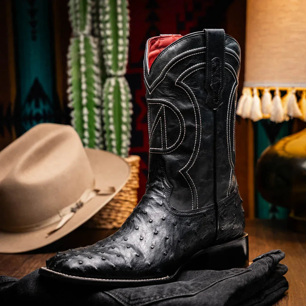 Man walking on dirt path wearing black ostrich skin cowboy boots with jeans.