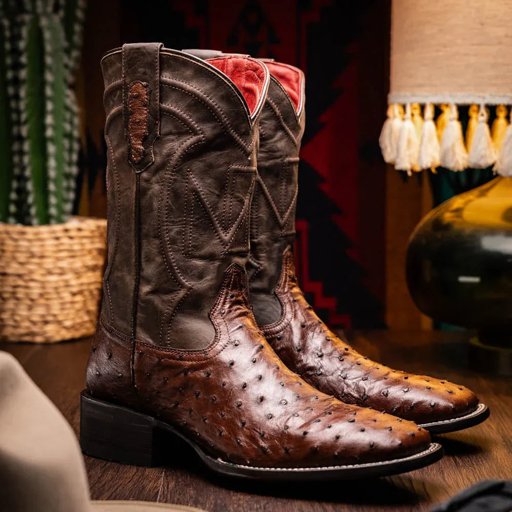 Man wearing brown ostrich skin Alabama cowboy boots standing on wooden floor