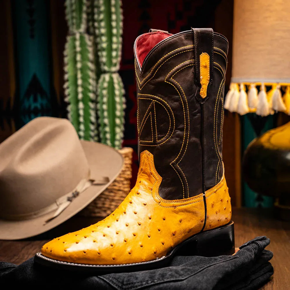Man wearing Alabama Buttercup ostrich skin cowboy boots walking on pavement.