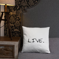 White pillow on a beige armchair next to a small wooden table with books