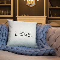 White square pillow on a cream upholstered chair by a window with natural light