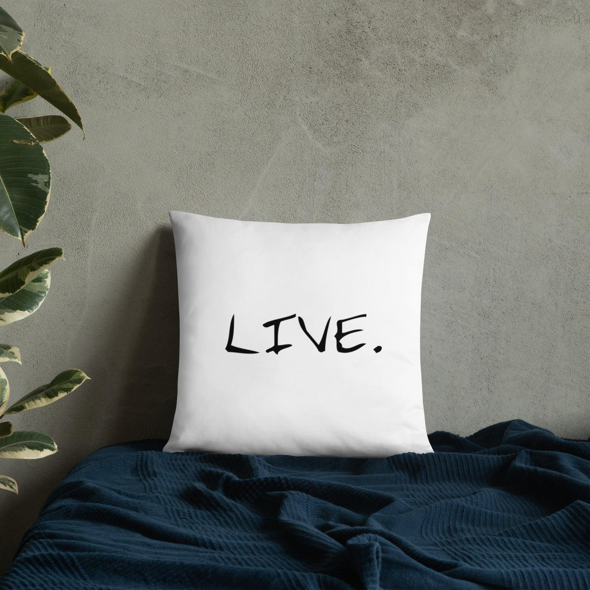 White square pillow on a beige chair near a wooden table with a laptop and cup