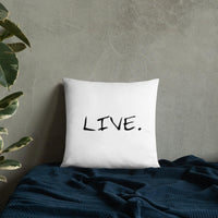 White square pillow on a beige chair near a wooden table with a laptop and cup