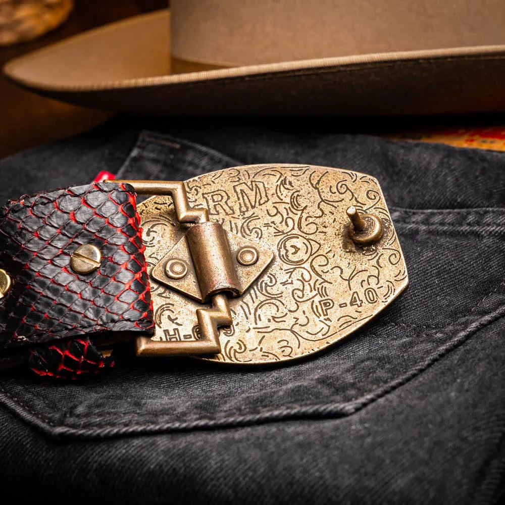 Man showing Arkansas Belt's antique brass buckle detail while dressed in cowboy outfit.