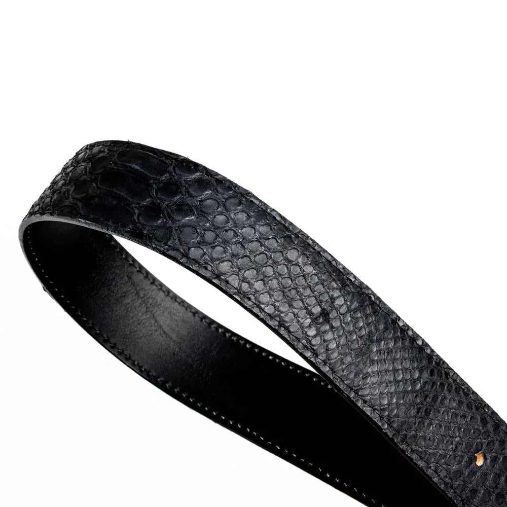 Arkansas black python belt coiled on white surface showcasing shiny brass buckle and leather interior