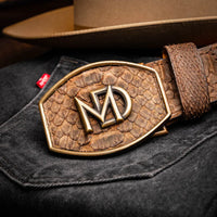 Man adjusting the brown python skin belt with antique brass buckle in an outdoor setting