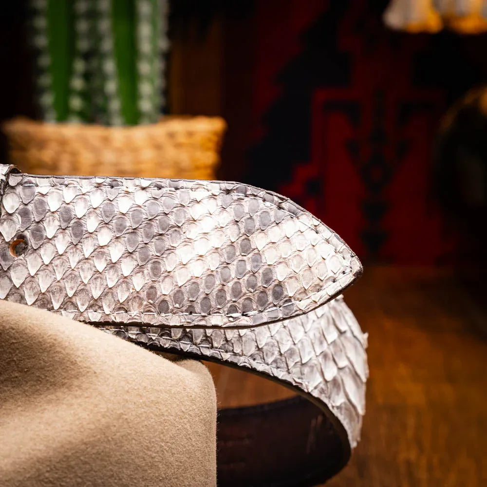 Man styling Arkansas python belt with rugged denim and leather jacket in urban setting.