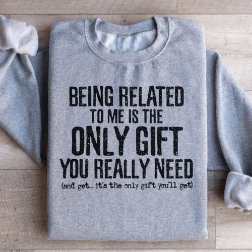 Close-up of light grey sweatshirt with bold text 'Being Related To Me Is The Only Gift You Really Need'.