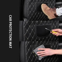 Detail shot of textured black car seat protector pad with red stitching against car interior backdrop.