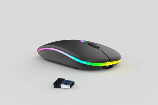 Black USB rechargeable RGB LED wireless mouse alongside keyboard and computer on desk.