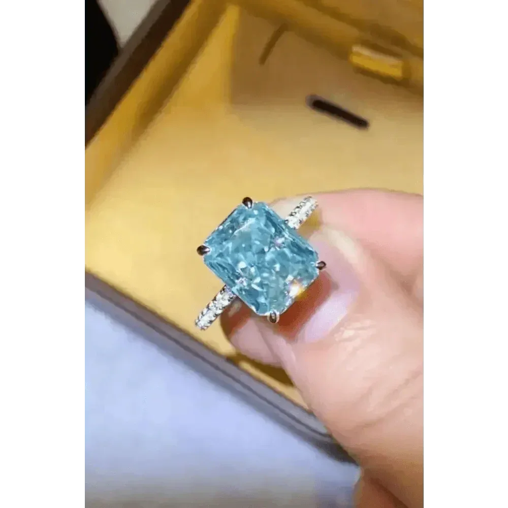 Close-up of blue gemstone 2 carat moissanite ring with green lighting reflection