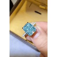 Close-up of blue gemstone 2 carat moissanite ring with green lighting reflection