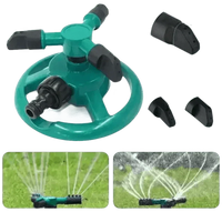 Water sprayed from blue rotating sprinkler covering garden grass area.