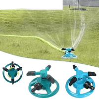 Side view of blue automatic rotating sprinkler watering healthy green lawn.