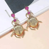 Side view of Bohemia earrings highlighting the gold-plated beetle shape and sparkling diamonds.