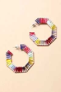 Side view of colorful raffia hoop earrings showcasing bold colors and woven detail on a plain background.