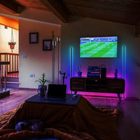 Black RGB LED corner floor lamp glowing with colorful lighting in a modern room corner.
