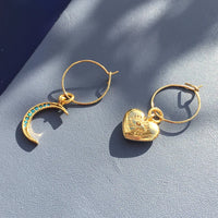 Detailed view of gold plated mini hoops with turquoise crystal moon and chunky heart charms.