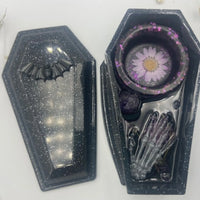 Handcrafted black resin coffin candle holder featuring amethyst stones, dried flowers, and central hole for incense.