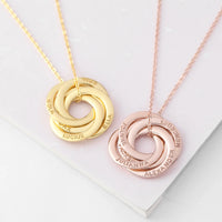 Hand holding silver personalized necklace with three interlocked rings symbolizing family bond.