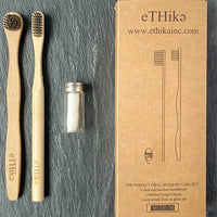 Bamboo toothbrush, tongue brush, and mint dental floss displayed neatly on wooden surface.