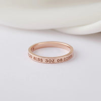 Personalized silver ring resting on textured fabric, highlighting fine engraving for new moms.