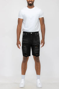 Close-up of the distressed fabric and button closure on men's denim shorts.
