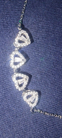 Side view of the silver LuckyClover heart and four-leaf clover necklace pendant on white.