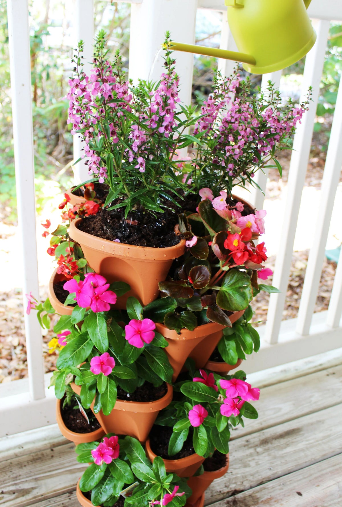 Stacked planters arranged outdoors, holding lush green herbs and small flowers in each tier.