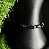 Black polished stone chip bracelet laid flat highlighting the irregular stone shapes.