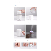 Small portable aroma diffuser connected via USB cable on office desk with laptop nearby.