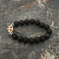 Close detail of silver skull bead surrounded by textured black lava stone beads on bracelet