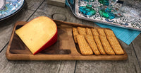 Elegant cheeseboard displaying assorted cheeses and crackers on rich end grain wood surface.