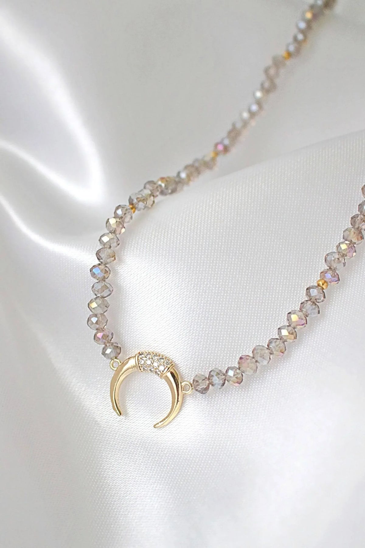 Light blue chrome Austrian crystal choker necklace laid flat highlighting crystals and gold charm pendant.