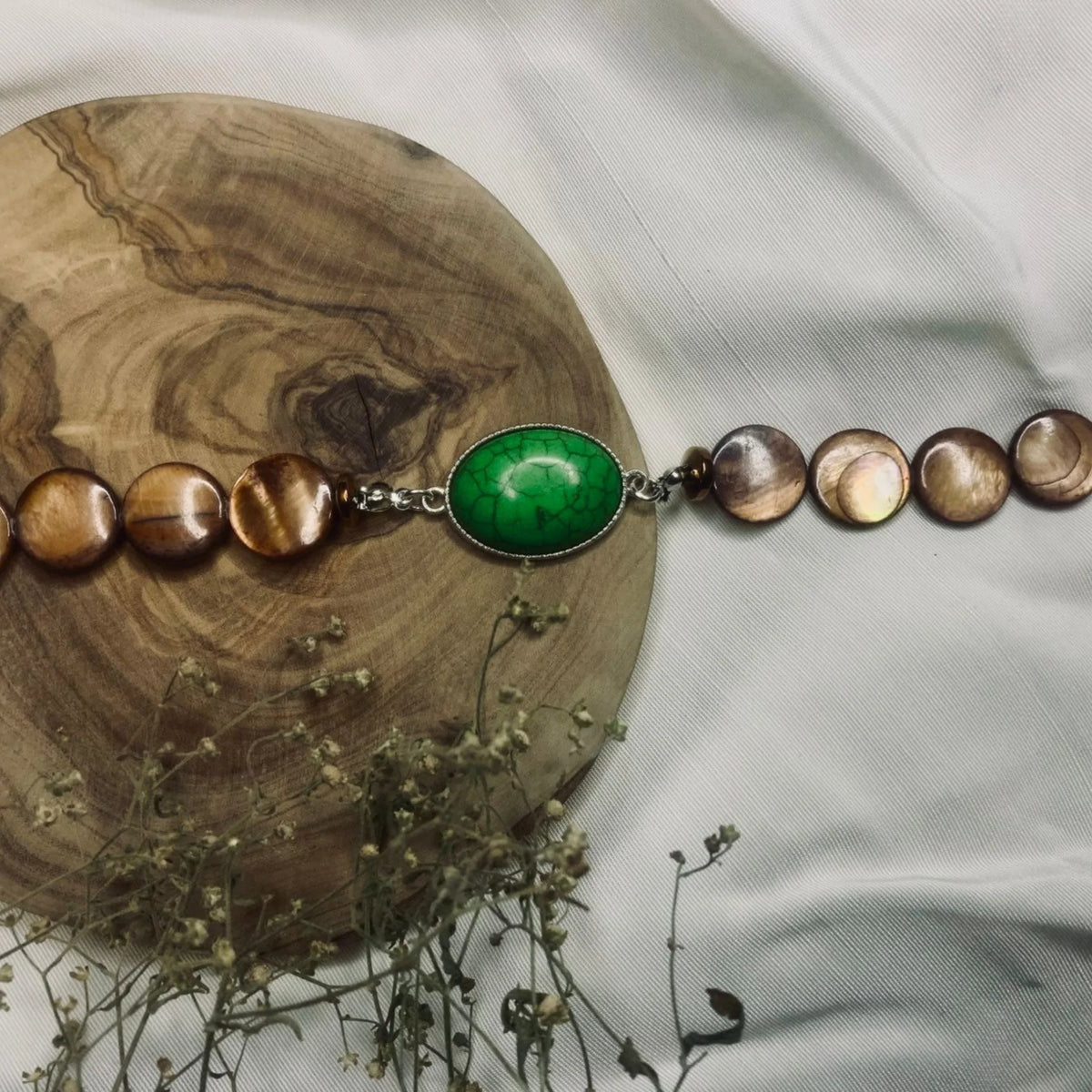 Handcrafted natural stone bracelet resting on a light surface showing texture and color.