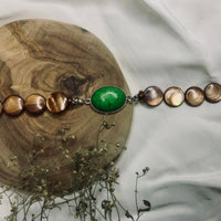Handcrafted natural stone bracelet resting on a light surface showing texture and color.