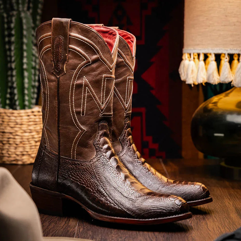 Lifestyle image of person wearing Denver Clear Brown ostrich leg cowboy boots outdoors on wooden steps.