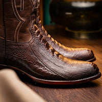 Side view of Denver Clear Brown ostrich leather cowboy boots worn with jeans in natural outdoor setting.
