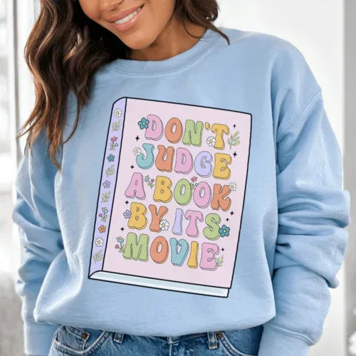 Light blue 'Don't Judge A Book' sweatshirt with peachy pink text, size small, warm fleece material.