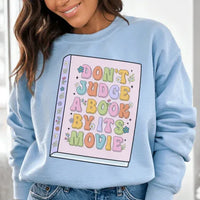 Light blue 'Don't Judge A Book' sweatshirt with peachy pink text, size small, warm fleece material.